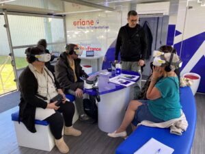 Plusieurs personnes participent à une activité immersive avec des casques de réalité virtuelle, accompagnées par un animateur dans un espace dédié à l’orientation.