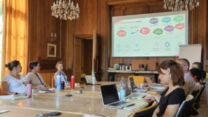 santé mentale CEAPSY COS Nanteau - Réunion de travail dans une salle en boiseries, avec des participants assis autour d'une grande table et un écran projetant une présentation.